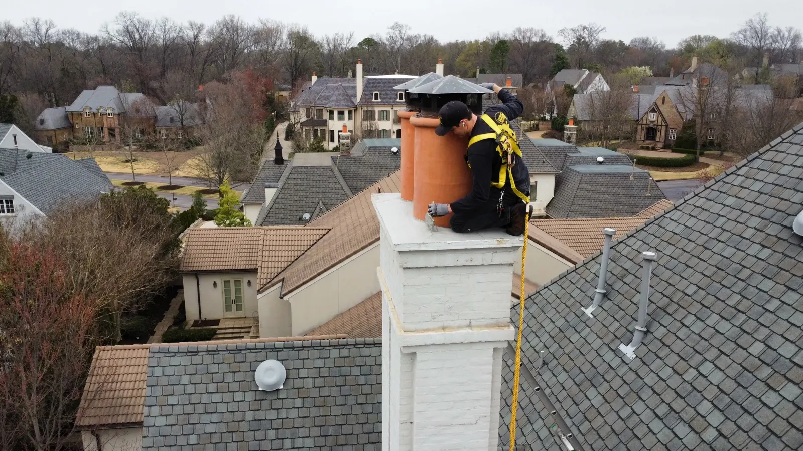 An Abbey Road technician working at the top of a rooftop chimney above a Memphis neighborhood