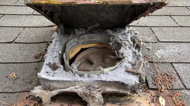 A rooftop dryer vent outlet packed with lint before cleaning