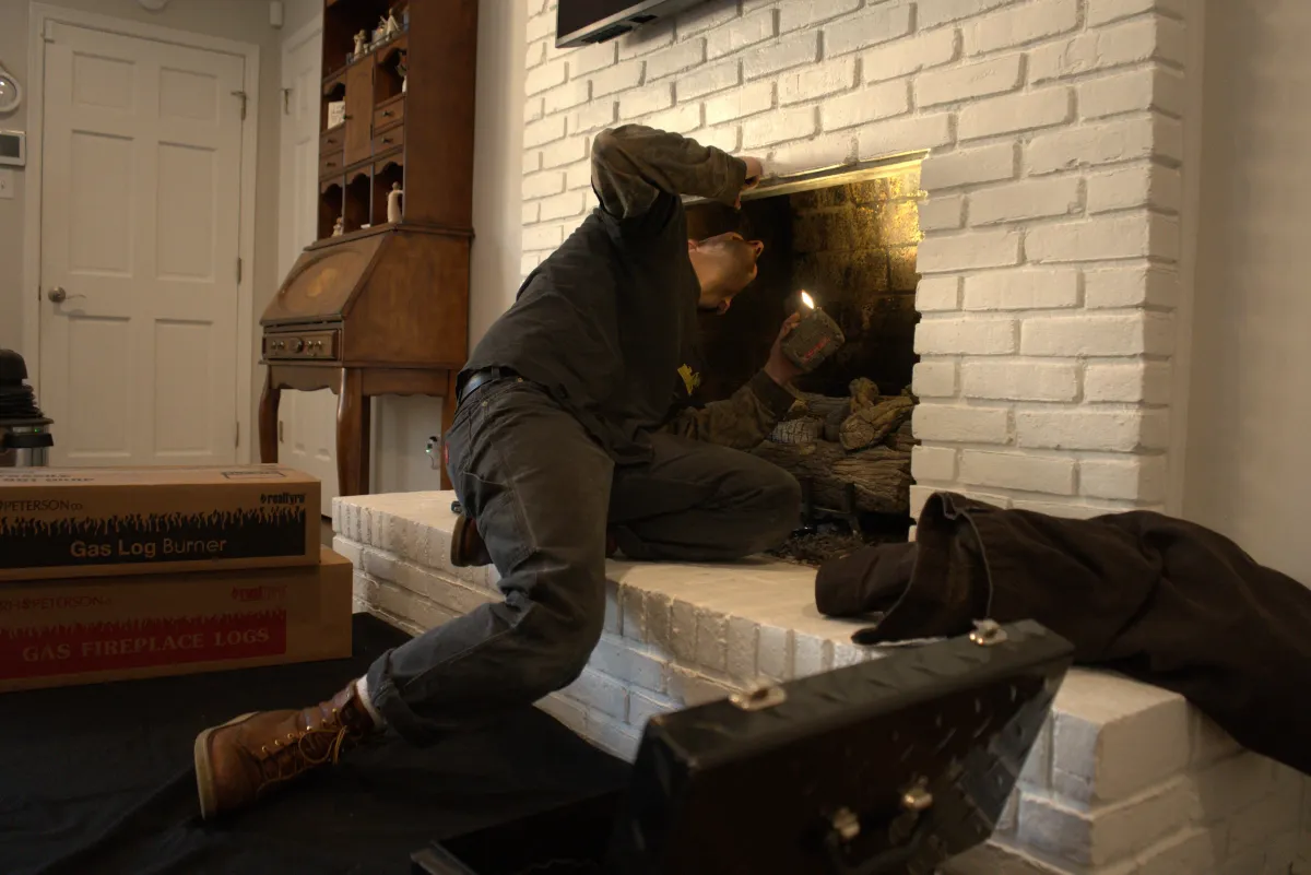Technician cleaning and inspecting a gas fireplace