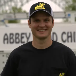 Timothy Weaver, owner of Abbey Road Chimney Sweep, in a branded Abbey Road cap and shirt in front of the company van